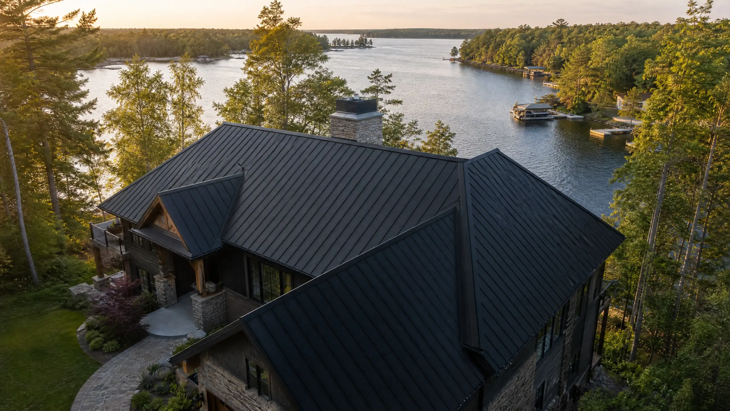 Luxury timber-frame chalet on the Whitefish Chain with a forest-green standing seam metal roof, private dock and open water beyond — Silver Loon Roofing